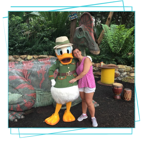 mujer posando para foto con persona disfrazada del pato Donald